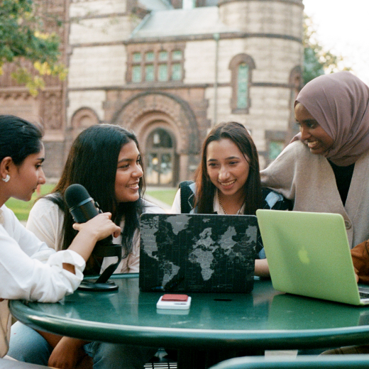 A picture of a group of women recording a podcast outdoors