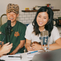 Two individuals smiling while recording tracks for a podcast