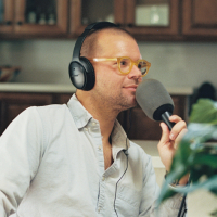 Man holding a microphone as he prepares to respond on a podcast