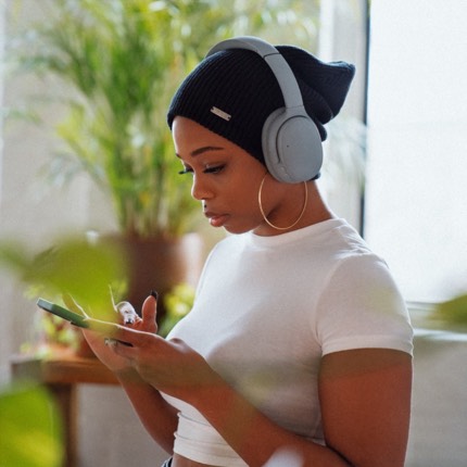 Woman listening to a podcast while looking at her phone. the text 'Spoitfy Audience Network' is overlayed on the bottom of the image