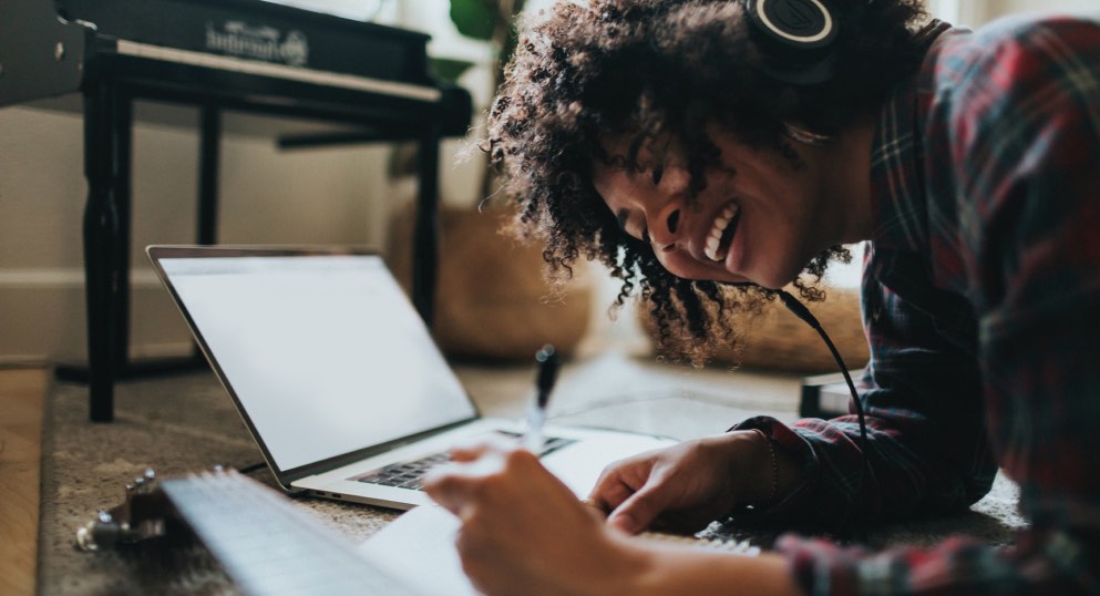 Smiling woman wearing headphones writing in a notebook